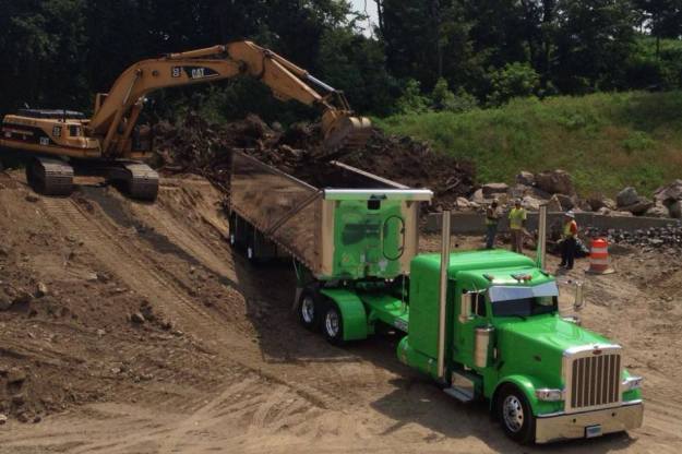 Get er Loaded Green Machine Semi Tractor and Shiney Matching Trailer getting loaded with Dirt with Backhoe Yellow Tracktor loadboard referatruck freight matching software for Truckers to make more money